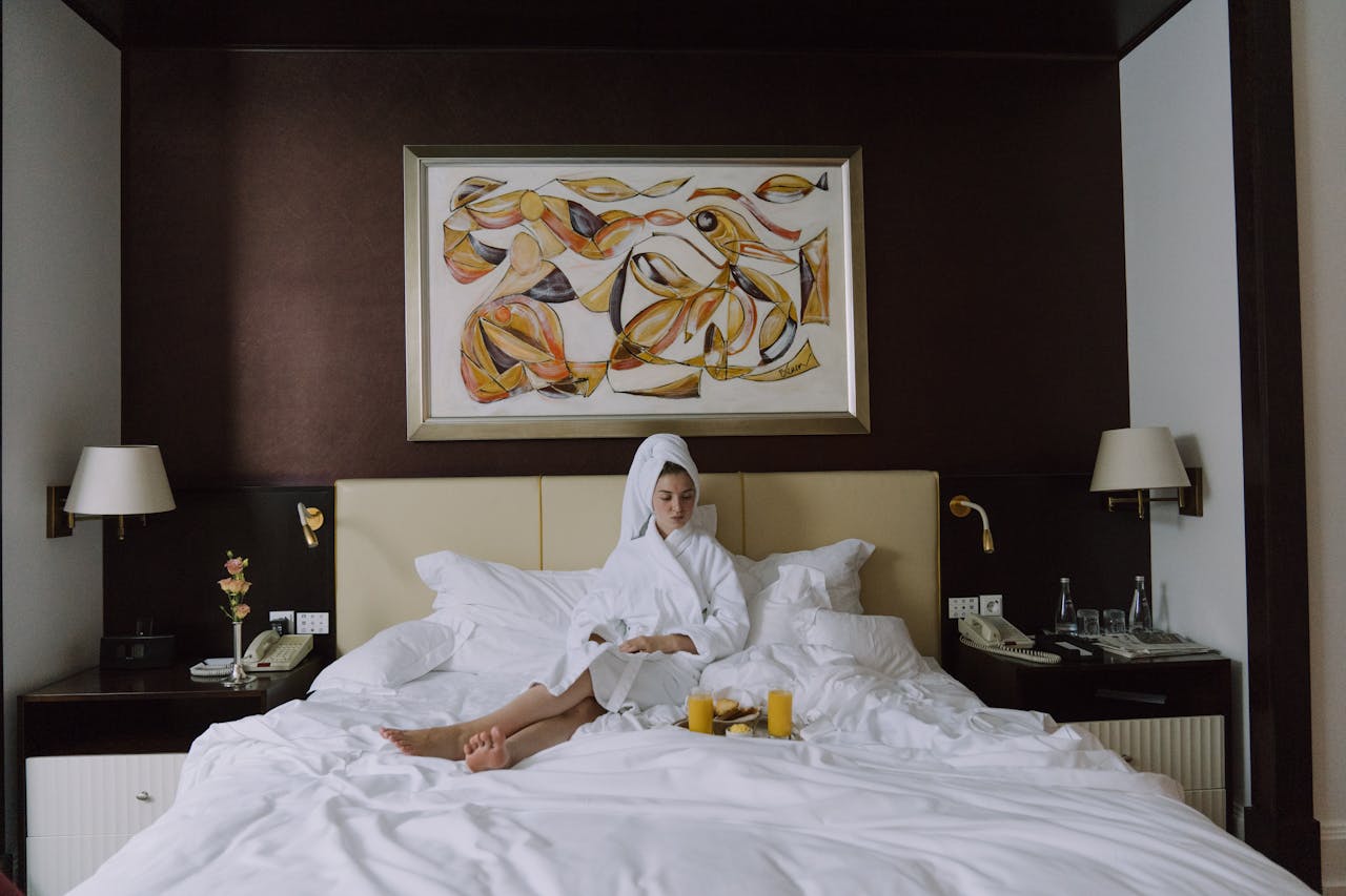 Woman enjoying breakfast in bed in a luxurious hotel setting, embracing relaxation and comfort.